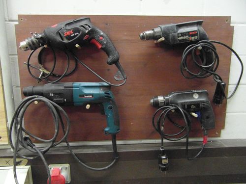 Different handheld electric drills on the wall.